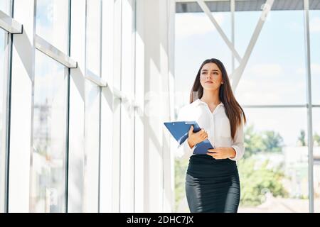 Uomo d'affari sicuro che va lavorare tenendo appunti in ufficio moderno Foto Stock