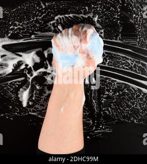 Processo di lavaggio delle mani con sapone blu, parti del corpo in schiuma bianca su fondo nero Foto Stock