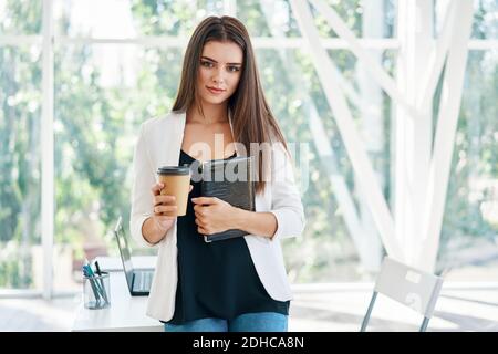 Ritratto di elegante uomo d'affari con una tazza di caffè in mano durante il tempo di pausa in un ufficio moderno Foto Stock