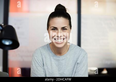 Ritratto di sorridere imprenditrice seduta in ufficio creativo Foto Stock