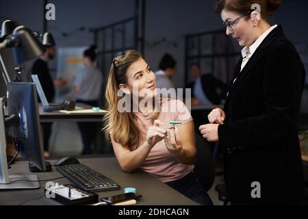 Donna d'affari creativa che discute con il responsabile della banca sopra l'automobile giocattolo solare in ufficio creativo Foto Stock