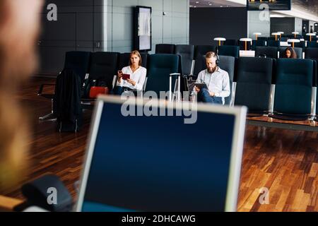 Uomini d'affari seduti in attesa del volo alla partenza dall'aeroporto area Foto Stock