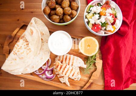Pollo pita wrap con pomodoro e patate tzatziki e un lato insalata greca Foto Stock