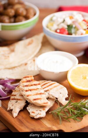 Pollo pita wrap con pomodoro e patate tzatziki e un lato insalata greca Foto Stock