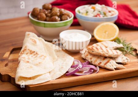 Pollo pita wrap con pomodoro e patate tzatziki e un lato insalata greca Foto Stock