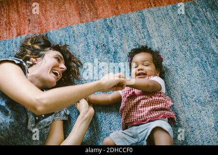 Vista ad alto angolo della madre felice e della figlia che giace sopra moquette a casa Foto Stock