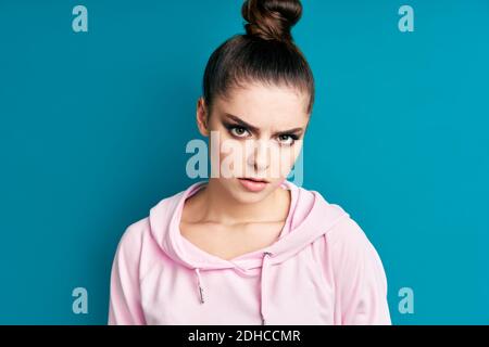 Giovane donna arrabbiata grave primo piano ritratto su sfondo blu Foto Stock