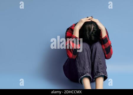 Giovane donna depressa seduta da sola sul pavimento Foto Stock