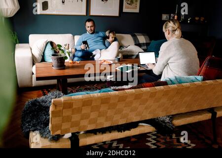Famiglia che utilizza varie tecnologie nel soggiorno Foto Stock