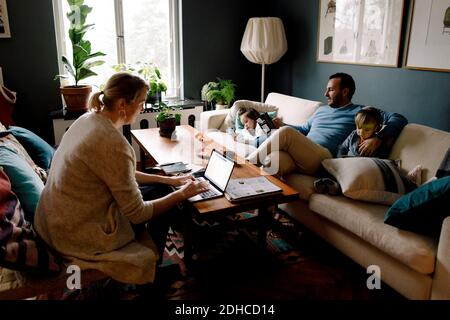Famiglia che utilizza varie tecnologie nel soggiorno di casa Foto Stock