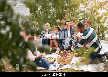 Famiglia felice e amici che hanno cibo sul lungolago nel parco Foto Stock