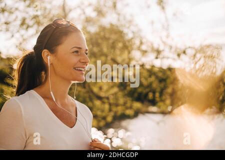Donna matura sorridente che parla con le cuffie in vacanza estiva Foto Stock