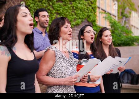 Cantanti corali multietnici che si esibiscono al di fuori della scuola di lingua Foto Stock