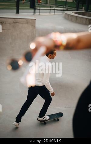 Vista ad alto angolo dello skateboard uomo da parte di un amico al parco Foto Stock