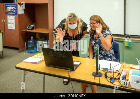 Solo in una classe a causa della pandemia del coronavirus, un insegnante della scuola elementare della California e il suo principale saluta il loro apprendimento virtuale a distanza Foto Stock