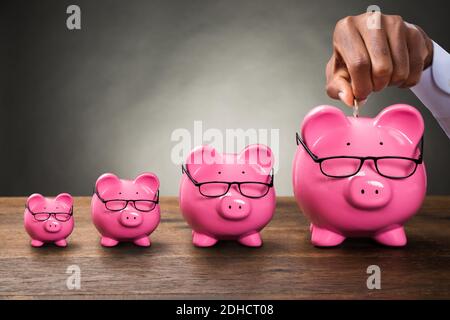Mano africana mettere moneta in Piggybank. Fondo di denaro pensionistico Foto Stock