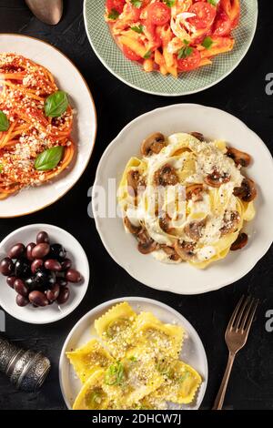 Pasta italiana, piatti vari, sparati dall'alto su sfondo scuro Foto Stock