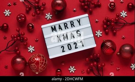 Concetto di sposare banner di Natale.Tabellone segnapunti bianco con testo scritta sposare Natale 2021 tra Natale rosso decorazione, palle, bacche, stelle e neve bianca Foto Stock