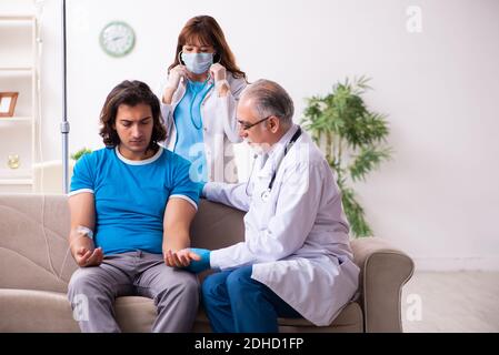 Due medici in visita a casa di un giovane malato Foto Stock