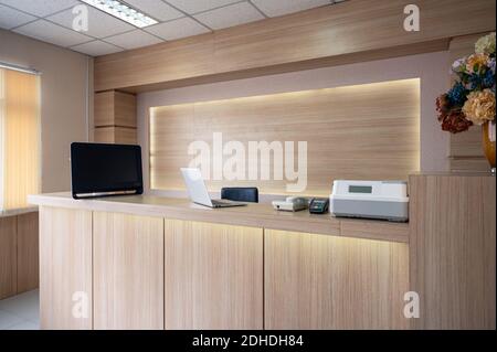 Banco di ricevimento vuoto e moderno in legno con monitor, computer portatile e dispositivo elettronico in ospedale Foto Stock