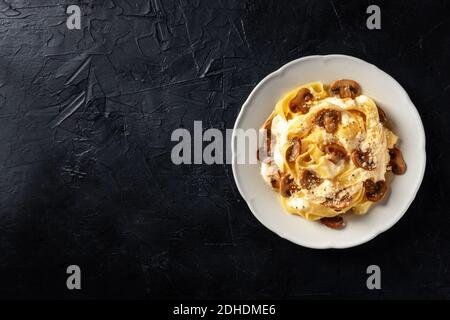 Pasta con funghi, salsa cremosa e parmigiano, sparato dall'alto su fondo scuro Foto Stock