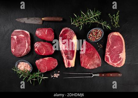 Carne, tagli vari, colpo di testa piatto con un coltello, una forchetta per barbecue, sale, pepe e rosmarino Foto Stock