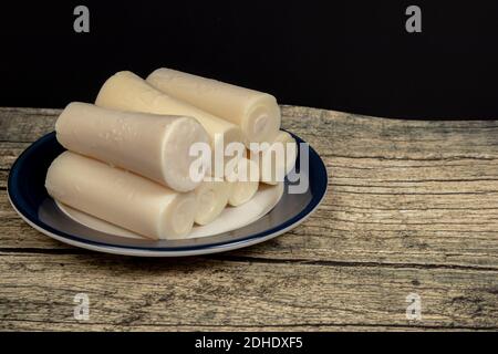 Palmetto intero o cuore di palma su una piastra su una superficie di legno con fondo nero. Concetto di cibo naturale, Foto Stock