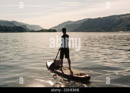 Una giovane donna pagaia un SUP sul fiume Columbia durante una giornata di sole. Foto Stock