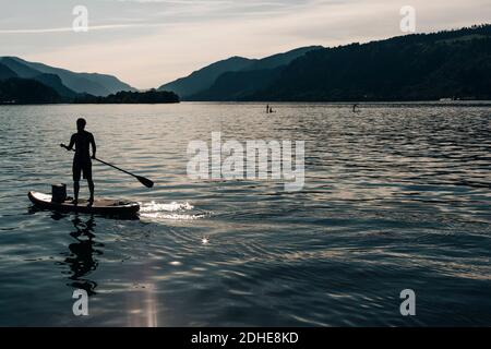 Una giovane donna pagaia un SUP sul fiume Columbia durante una giornata di sole. Foto Stock