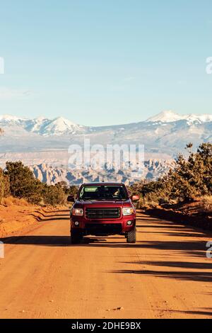 Camion rosso pick-up centrato in strada sterrata nel deserto vicino Moab, Utah Foto Stock