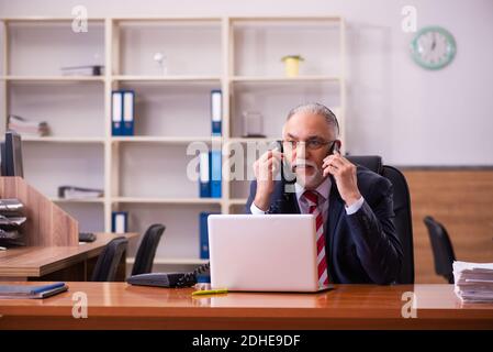 Vecchio dipendente di sesso maschile seduto in ufficio Foto Stock