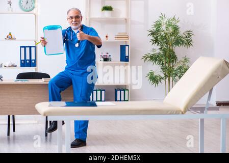 Medico di sesso maschile anziano che prende appunti in clinica Foto Stock