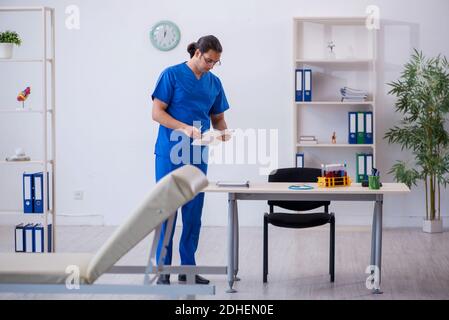 Giovane medico di sesso maschile prendendo appunti in ospedale Foto Stock
