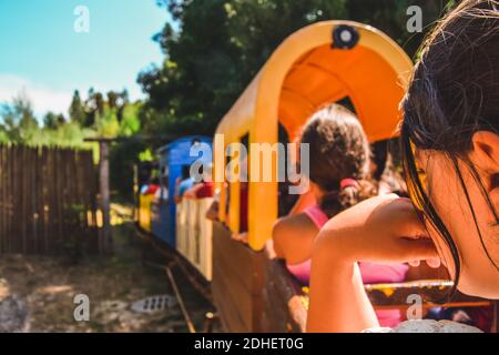 I bambini trascorrono del tempo nel parco per bambini viaggiando in trenino in una giornata di sole Foto Stock