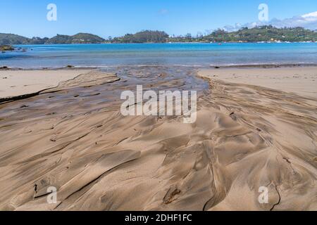 Modelli in creato da acqua da piccolo flusso di lavaggio attraverso spiaggia al bordo dell'acqua Foto Stock