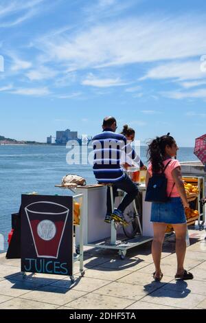 Mand pedalando sulla macchina Street Juice Vendors a Lisbona, sistema di pedalare per fare bevande succose per le strade per i turisti Foto Stock