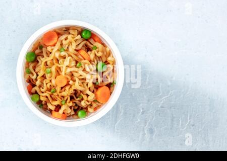 Tagliatelle istantanee in una tazza di plastica, sparate dall'alto Foto Stock