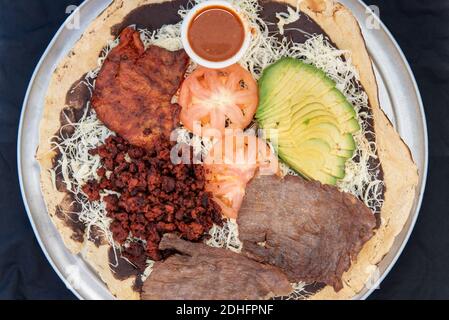 Vista dall'alto del piatto taco del campionatore da condividere con la famiglia, tra cui bistecca di carne asada, hamburger, pollo al pollo, avocado e condimenti di pomodoro. Foto Stock