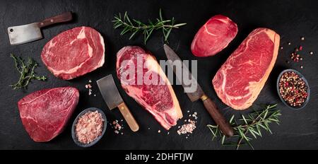 Panorama della carne. Varie bistecche di manzo, un piatto top shot su uno sfondo nero Foto Stock