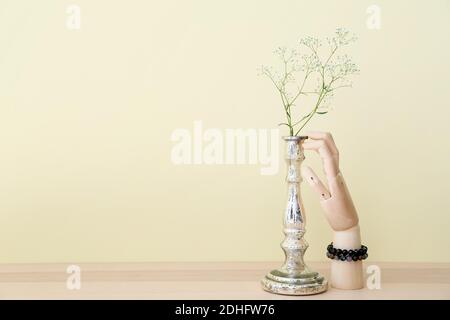 Mano di legno in braccialetti e vaso con fiori sul tavolo Foto Stock