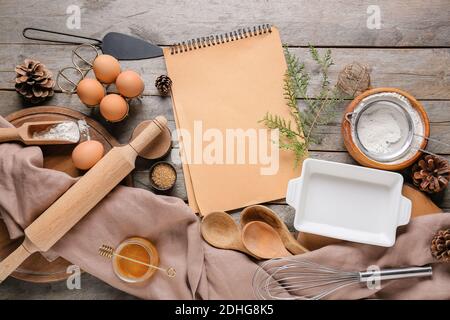 Notebook con ingredienti per panetteria di Natale e utensili da cucina su sfondo di legno Foto Stock