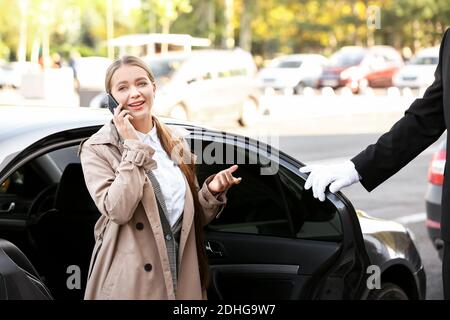 Giovane donna d'affari che esce dall'auto di lusso Foto Stock