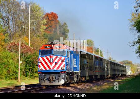 Ginevra, Illinois, Stati Uniti. Un treno per pendolari Metra emerge dall'ombra al sole di un pomeriggio d'autunno mentre passa attraverso Ginevra, Illinois. Foto Stock