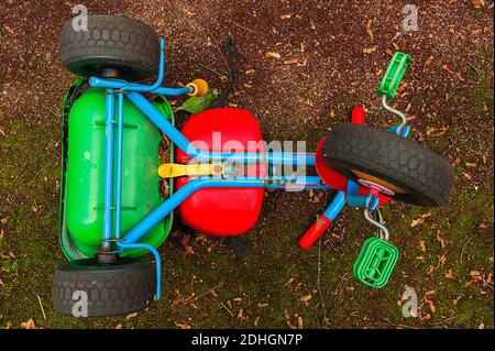 Triciclo verde e blu per bambini capovolto Foto Stock