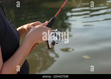 Le mani del pescatore stanno pescando su una pesca filante, giorno estivo soleggiato. Foto Stock