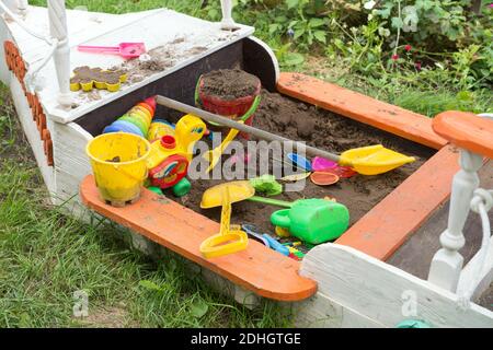 Sandpit per bambini sotto forma di barca con giocattoli sparsi e luminosi. Foto Stock