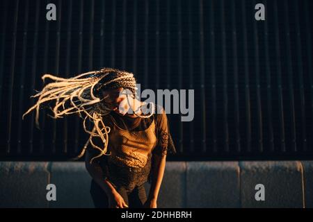 Sorridente ragazza adolescente danzare con capelli lunghi tosati a skateboard parcheggio Foto Stock