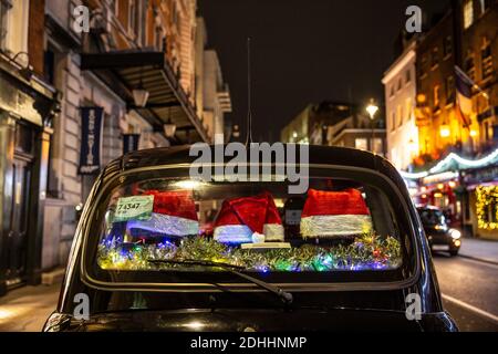 Un taxi sul retro con i cappelli natalizi di Santa che decorano la sua finestra sul retro si trova a Covent Garden, Londra, Inghilterra, Regno Unito Foto Stock