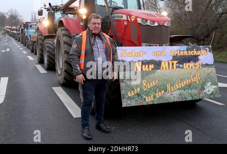 Rostock, Germania. 11 Dicembre 2020. Toni Reincke, co-organizzatore della sfilata dei trattori, si trova all'inizio di una sfilata di trattori davanti ad un trattore, al quale è apposta un grande cartello con l'iscrizione 'natura e protezione delle specie? Solo CON noi! Il vostro agricoltore dal quartiere'. Con questa azione gli agricoltori vogliono protestare contro norme ambientali più severe. Credit: dpa Picture Alliance/Alamy Live News Foto Stock