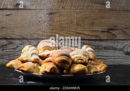 Biscotti fatti in casa sotto forma di bagel con marmellata di ripieno cosparso di zucchero in polvere su uno sfondo di legno. Messa a fuoco selettiva. Foto Stock